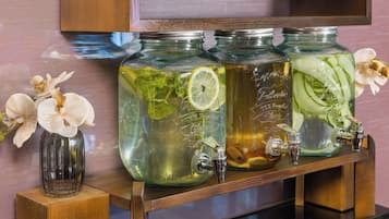 Trois bocaux en verre munis de robinets, chacun contenant différents liquides et décoré de différents éléments, sont placés sur une étagère en bois.