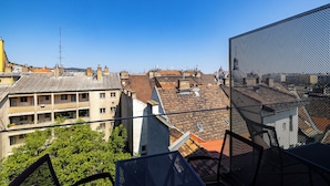 Vista de un paisaje urbano con varios edificios, incluyendo un edificio amarillo destacado con techo plano y una gran estructura de malla en primer plano.