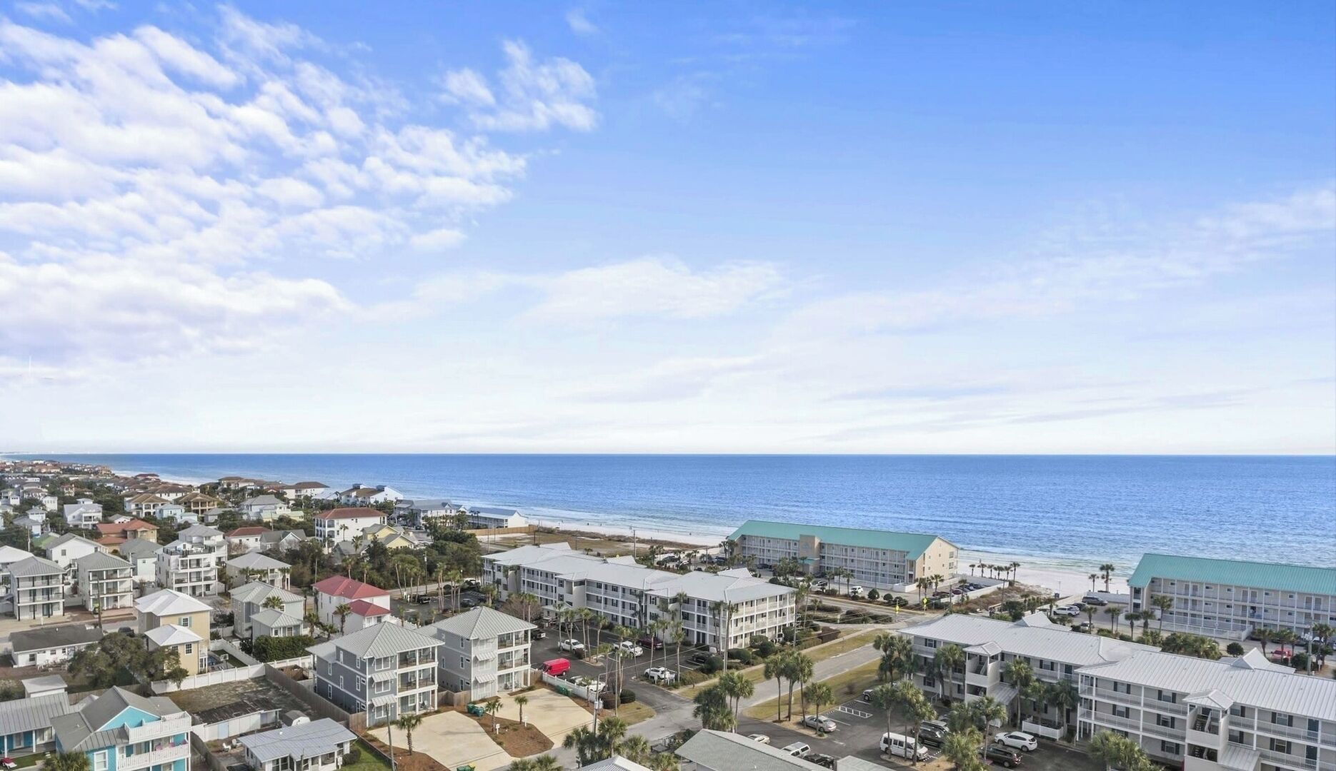 Un quartier résidentiel situé sur la côte, avec des propriétés en bord de mer, notamment des immeubles à plusieurs étages et des maisons unifamiliales, offrant une vue dégagée sur l’océan.