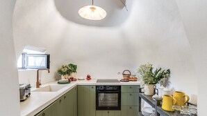 A kitchen with green cabinets, a black oven, and a window with a view. - Trullo Il Nuciareddo (Ostuni)