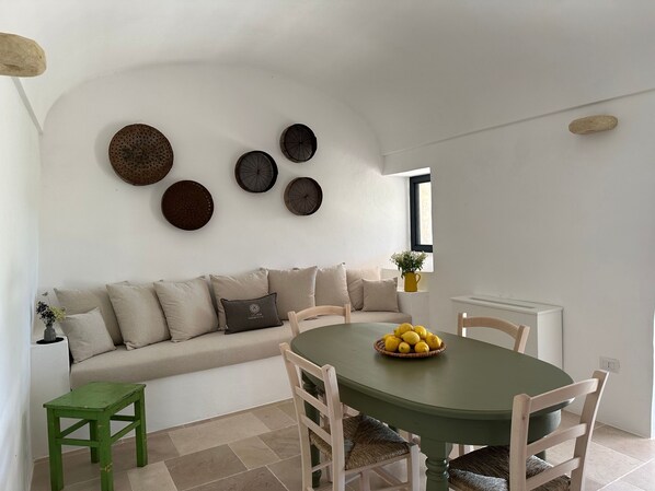 Un coin repas comprenant une table ronde, des chaises, un canapé et des assiettes décoratives accrochées au mur.