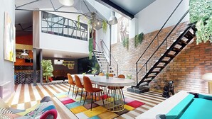 Un intérieur moderne comprenant un coin repas, une table de billard et un escalier.