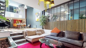 Un salon moderne avec un canapé, une table basse en verre et un escalier menant à un niveau supérieur.