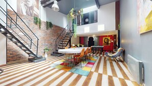 Un intérieur moderne comprenant un coin repas, une table de billard et un escalier adossé à un mur en briques.