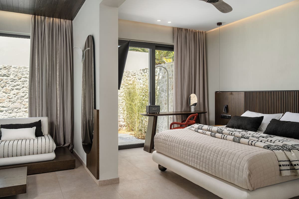 A modern bedroom with a bed, a sofa, a desk, and a large window.