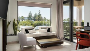 A modern living room with a sofa, a coffee table, and a dining area with a table and chairs. - Dyo Beach Suites (Rethymno)