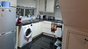 Una cocina compacta equipada con lavadora, microondas, tostadora y cocina a gas.