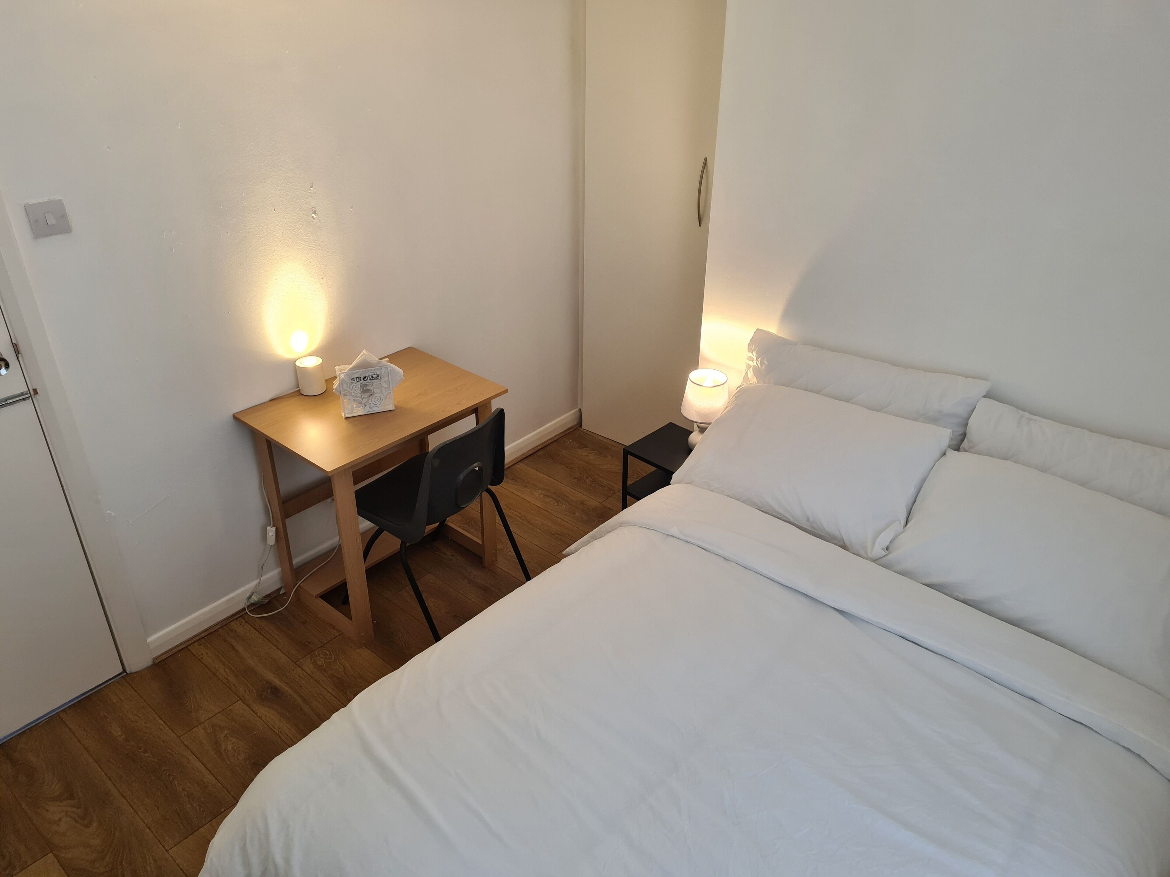 A bedroom with a bed, a desk with a chair, and two bedside lamps.