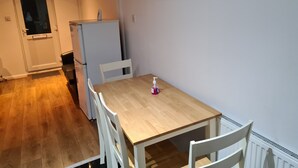 Una cocina compacta con una mesa y sillas de madera, un refrigerador y una puerta que da a otra habitación.