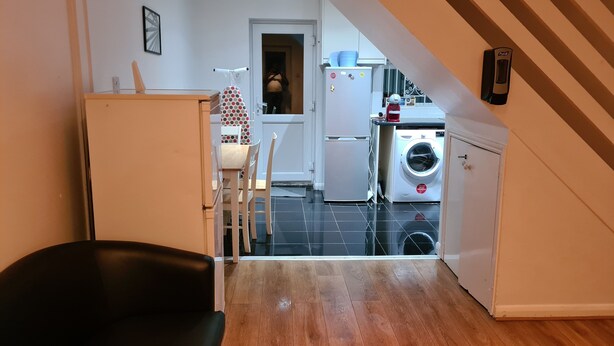 Una cocina compacta con lavadora, refrigerador y comedor con mesa y sillas.