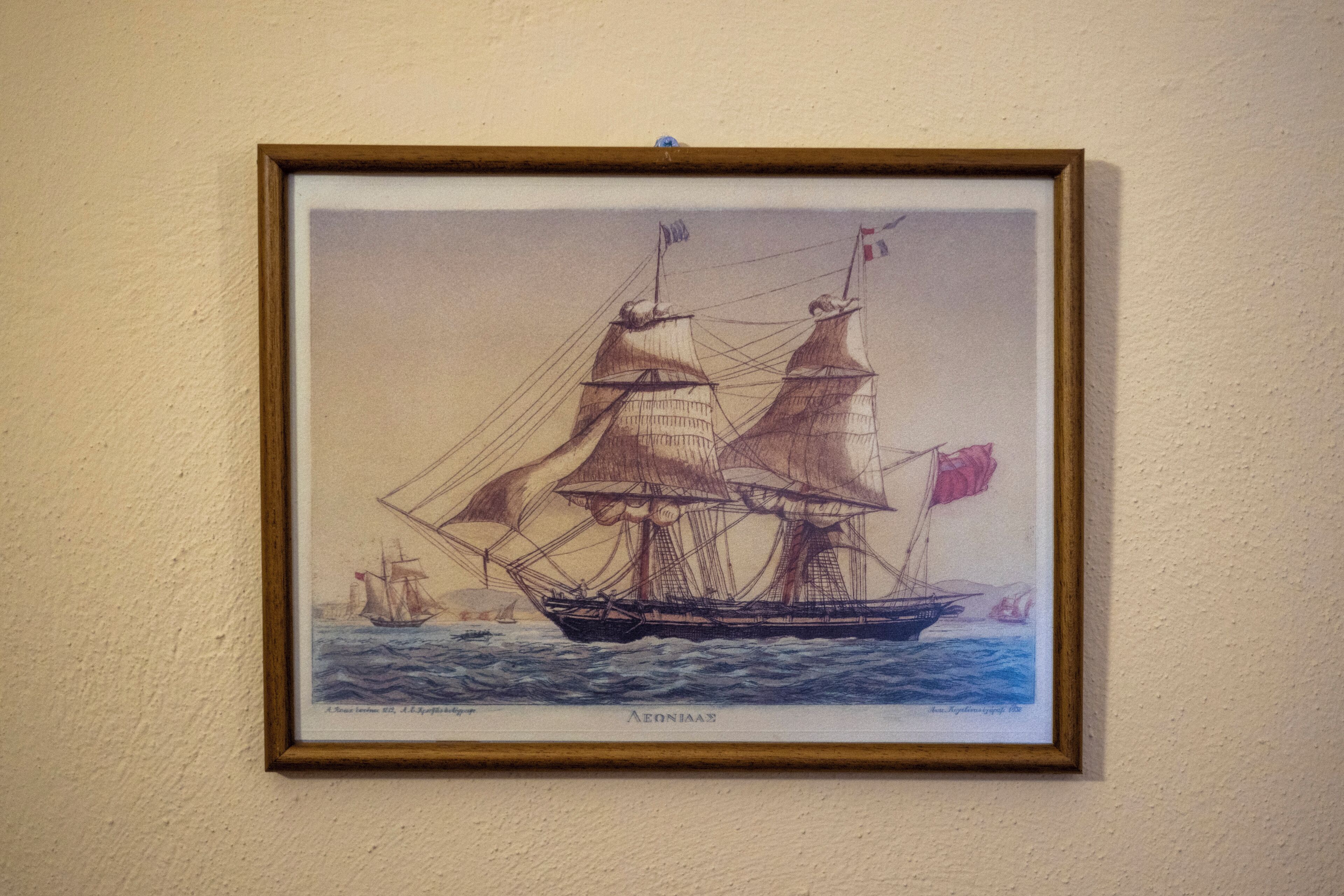 A framed maritime painting of a sailing ship on the sea.
