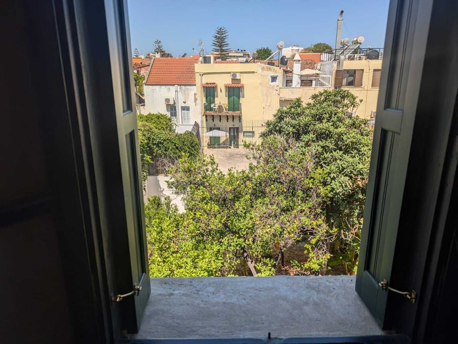 A view from a window overlooking a residential area with buildings and greenery.