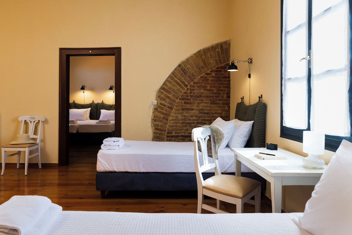 A hotel room with a bed, a desk, a chair, and a window.