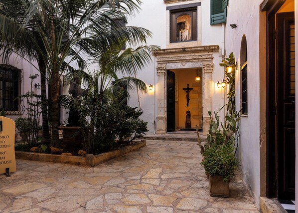 Stroll through the serene courtyard, surrounded by potted plants and a historic entrance with a classical architectural style.