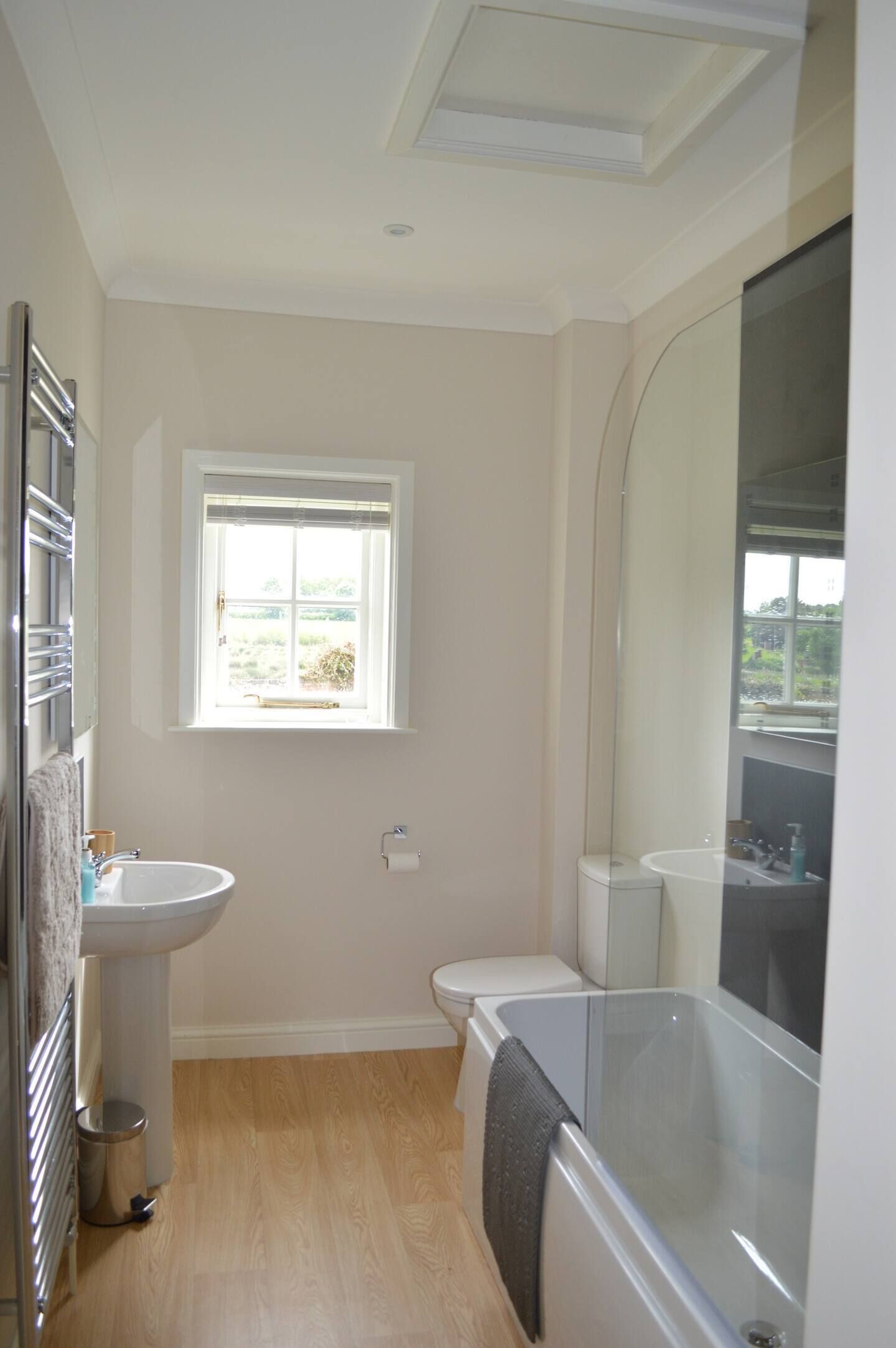 Een badkamer met een raam, een wastafel, een toilet en een bad.