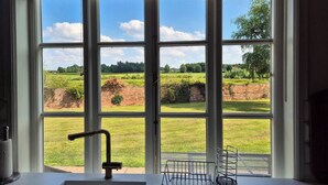 A kitchen with a large window, a sink, and a metal rack.