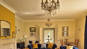 A living room with two blue sofas, a chandelier, and a fireplace.