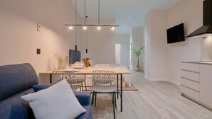 Una cocina moderna con comedor, un sofá y un televisor montado en la pared.