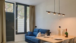 Una sala moderna con un sofá azul, una mesa de comedor con sillas y una araña.