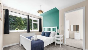 A bedroom with a bed, bedside table, and a window with curtains.