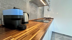 Une cuisine moderne dotée d’un plan de travail en bois, d’une machine à café Nespresso, d’une cafetière en acier inoxydable et d’un élégant pare-éclaboussures.