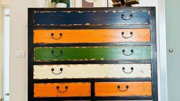 A multi-tiered wooden dresser with variously colored drawers, each with a handle.