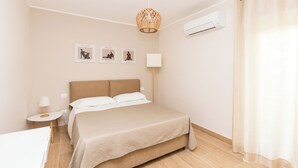 Ein ordentlich eingerichtetes Schlafzimmer mit einem Bett, Nachttischen, einer Lampe und Wandbildern.