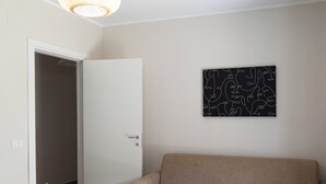 Ein Essbereich mit einem weißen Tisch, gedeckt für vier Personen, einem beigen Sofa und einem schwarzen, abstrakten Kunstwerk an der Wand.
