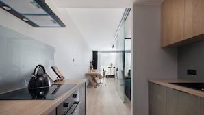 A modern kitchen with a kettle, a wooden countertop, and a glass partition leading to a dining area with a table and chairs. - EASY RENT Apartments - Brilliant (Lublin)
