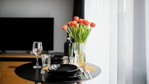 A dining table with a black tablecloth, a vase of orange tulips, a bottle, and several glasses. - EASY RENT Apartments - Brilliant (Lublin)