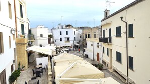 A narrow street with buildings on both sides, outdoor seating areas, and a few potted plants. - Apartment in the heart of Otranto (Otranto)
