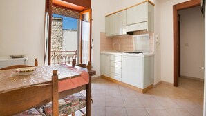 A small, bright kitchen with white cabinets, a sink, and a window overlooking a stone wall. - Apartment in the heart of Otranto (Otranto)