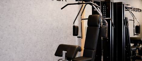 A gym with a wall-mounted mirror, a weight bench, and a squat rack.