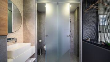 A modern bathroom with a glass-enclosed shower, a white sink, and a large mirror.
