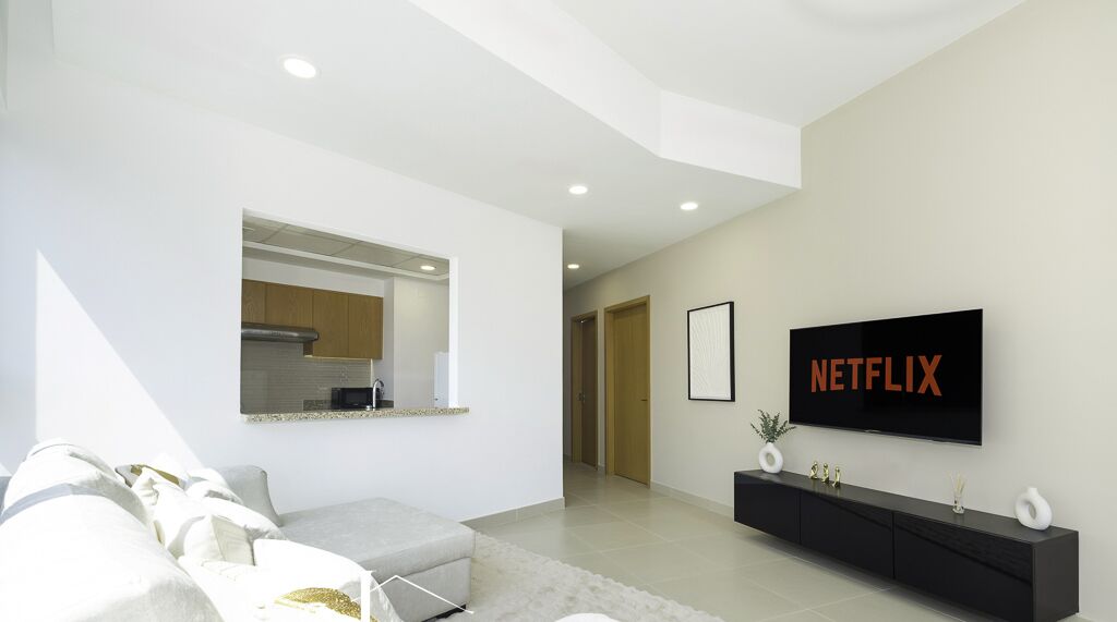 A modern living room with a sofa, a TV mounted on the wall, and a console table.