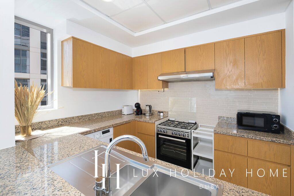 A modern kitchen with granite countertops, stainless steel appliances, and wooden cabinets.