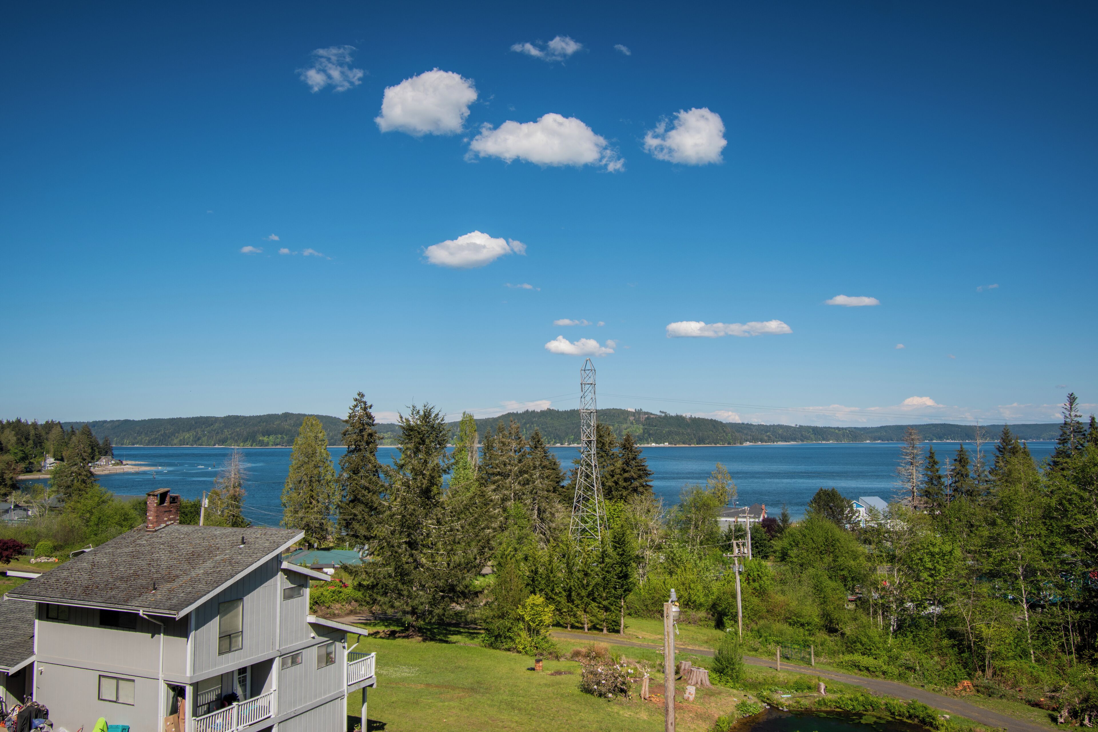 A residential area with a house, a dock, and a clear view of a large body of water.
