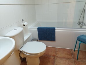 A bathroom with a toilet, sink, bathtub, and a blue towel. - Peaceful and Stylish Cottage Near Taunton Somerset (Taunton)