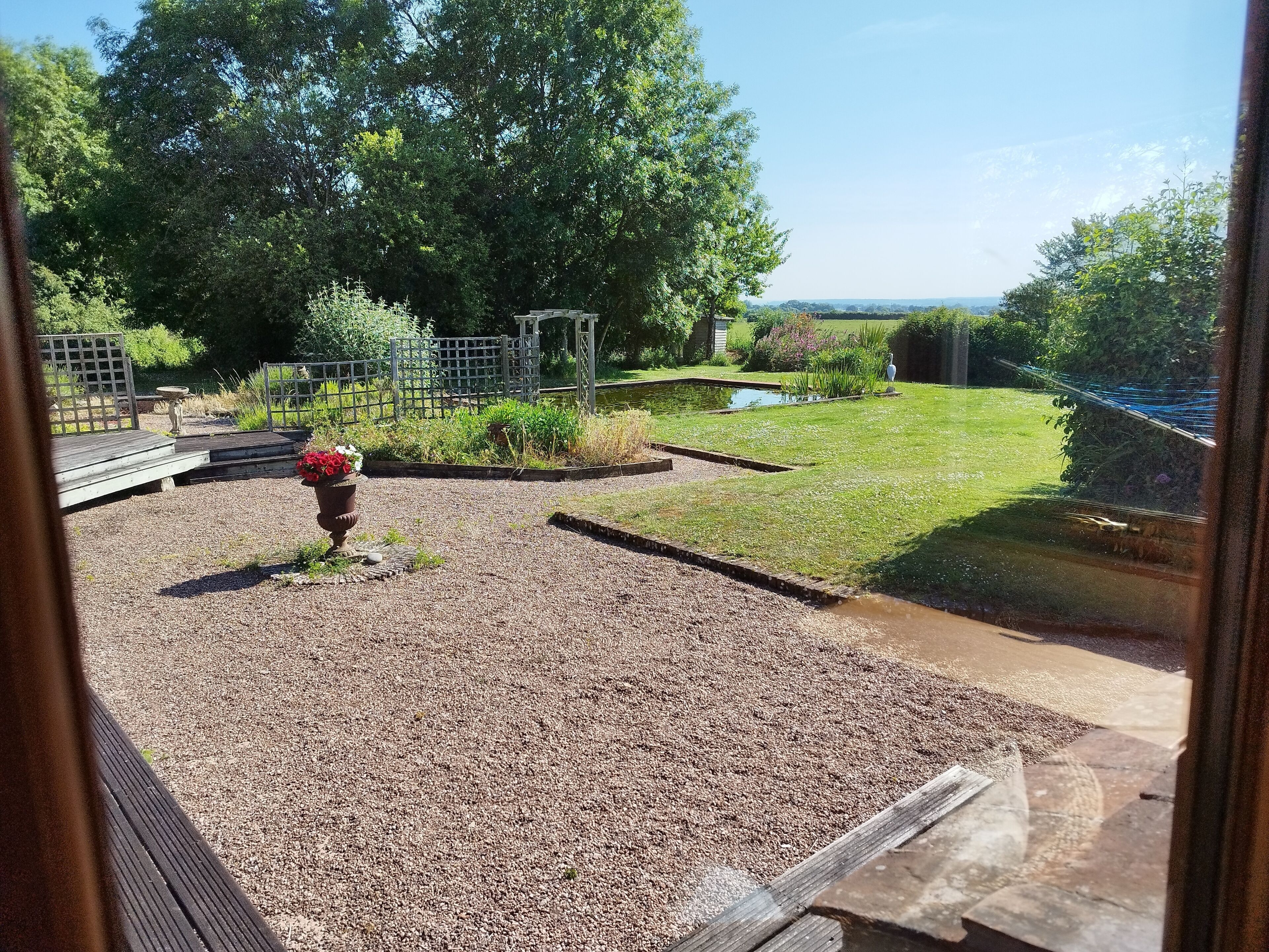 A garden with a gravel area, a wooden deck, and a pond.