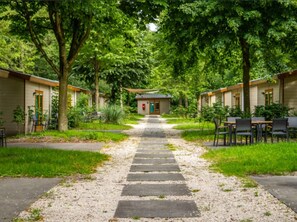A pathway leading to a row of single-story buildings with outdoor seating areas.