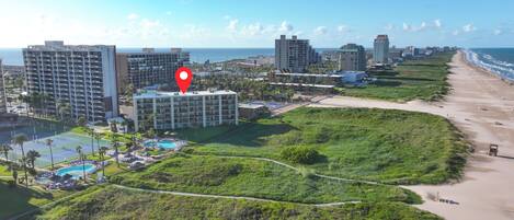 Un hotel costero con varios edificios altos, una playa y una zona de piscina.