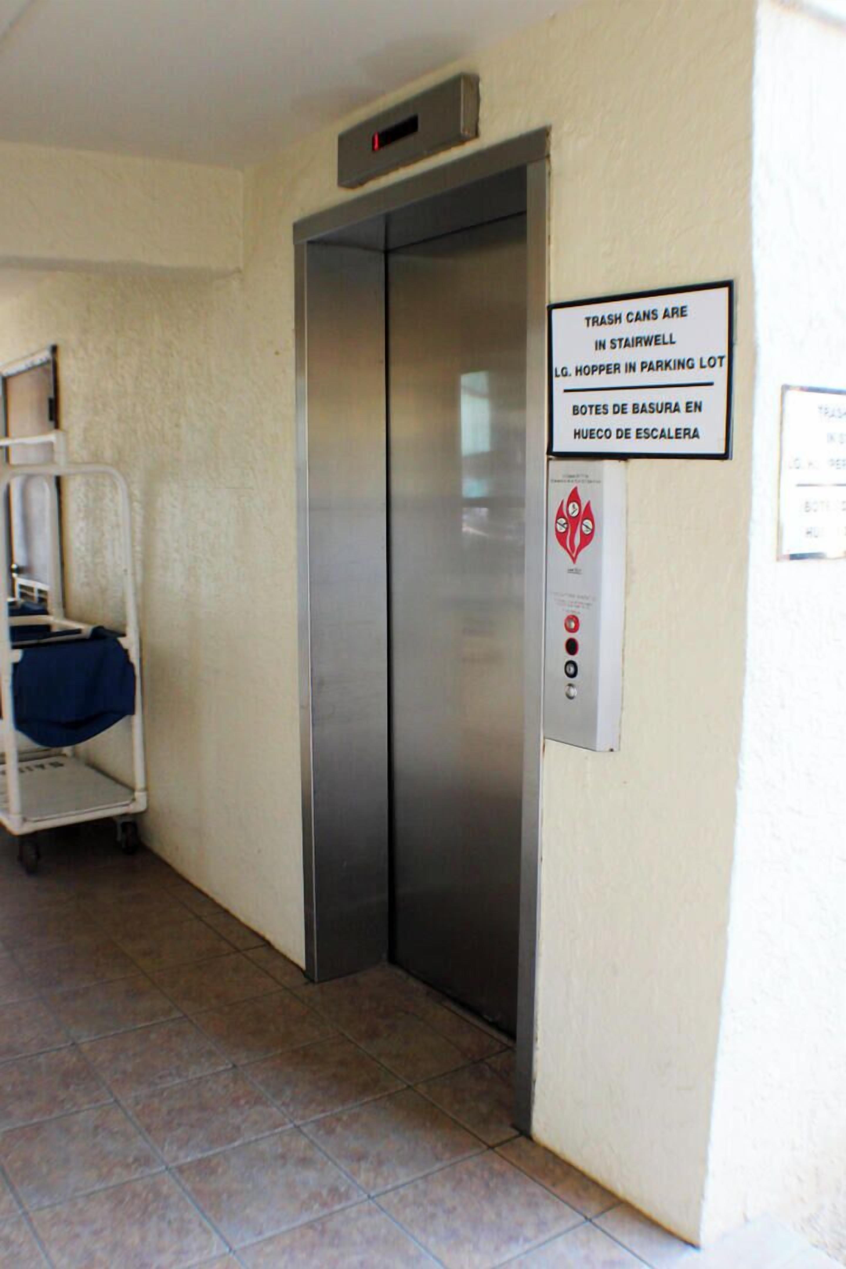 Un ascensor con un cartel que indica contenedores de basura en la escalera y el estacionamiento.