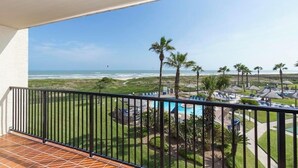 Een balkon met uitzicht op een strand en een zwembad.