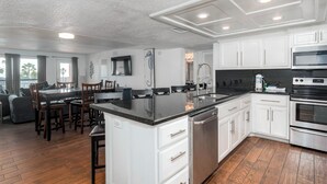 Een moderne keuken met witte kasten, een zwart aanrecht en roestvrijstalen apparatuur.