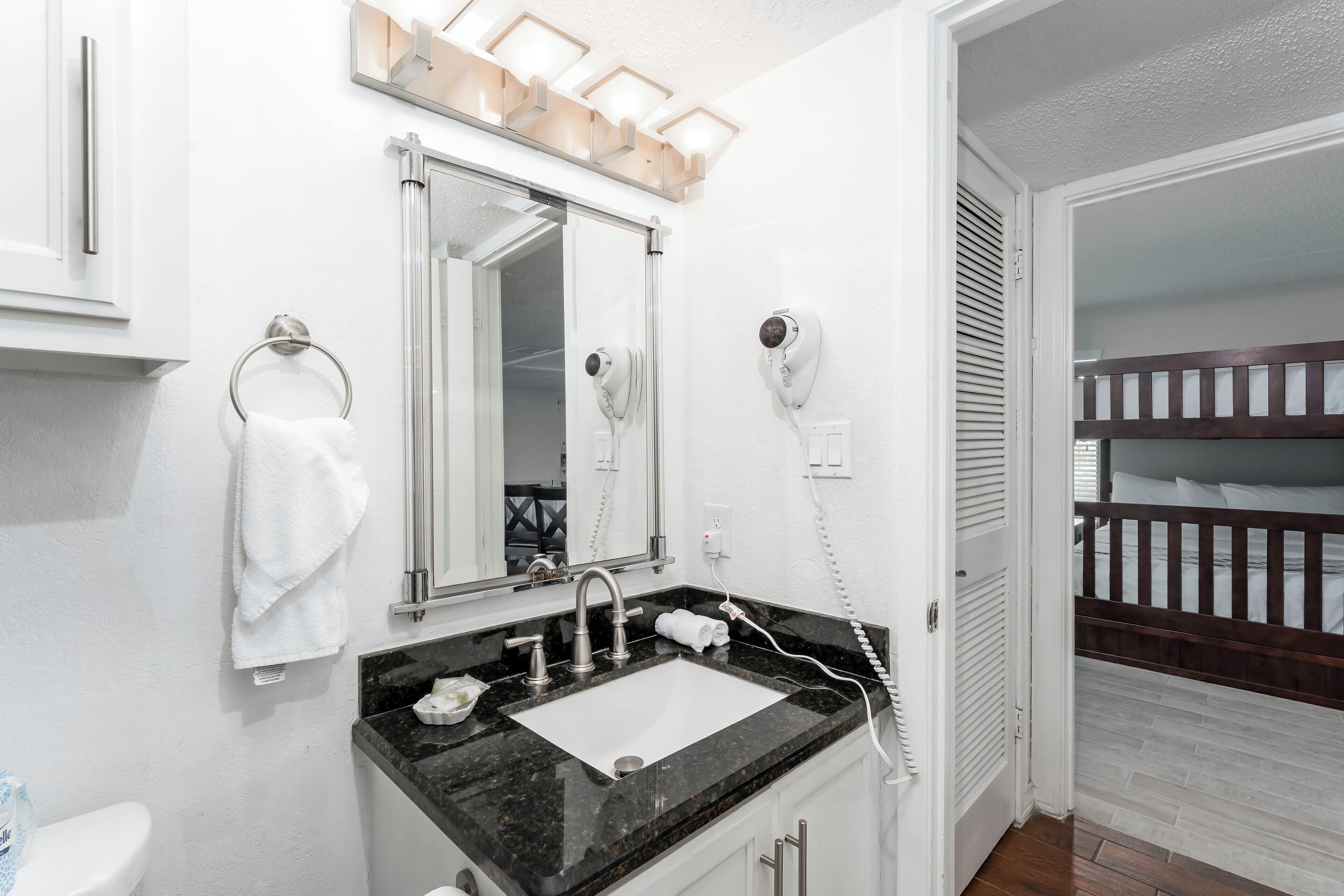 A bathroom with a sink, mirror, towel rack, and hairdryer.