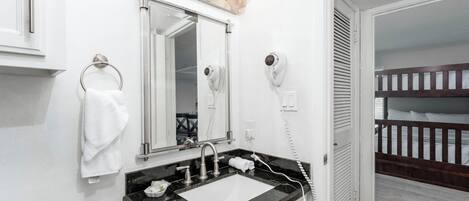 A bathroom with a sink, mirror, towel rack, and hairdryer.