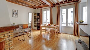 A spacious living area with a wooden ceiling, a dining table with chairs, a sofa, and a bookshelf. - Charming 1BR near Eiffel Tower & Les Invalides (Paris)