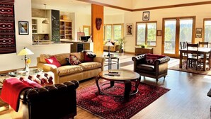 A spacious living room with a high ceiling, a fireplace, and a dining area with a view of the outdoors. - The Alpine Vista | Pets | Couples | Golf | Nakoma (Portola)