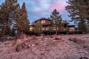 A two-story lodge with a wooden exterior, surrounded by pine trees and large rocks. - The Alpine Vista | Pets | Couples | Golf | Nakoma (Portola)