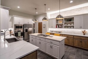A modern kitchen with white cabinetry, stainless steel appliances, and pendant lighting. - The Alpine Vista | Pets | Couples | Golf | Nakoma (Portola)